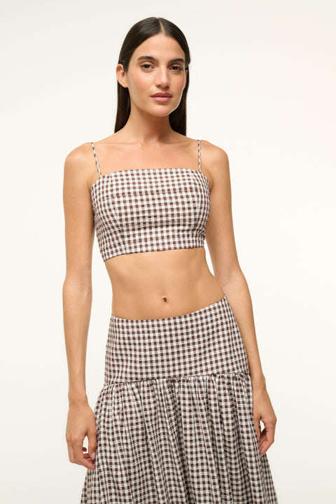 Up close shot of a woman wearing a brown gingham crop top and a matching skirt 