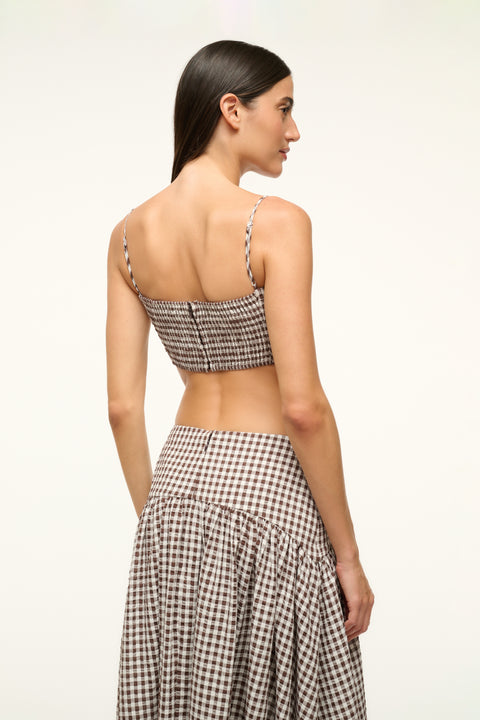 Up close back view of a woman wearing a brown gingham crop top with a matching skirt.