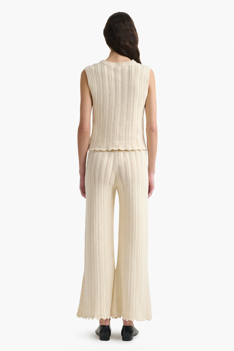 Back of woman wearing cream knitted top and pant.