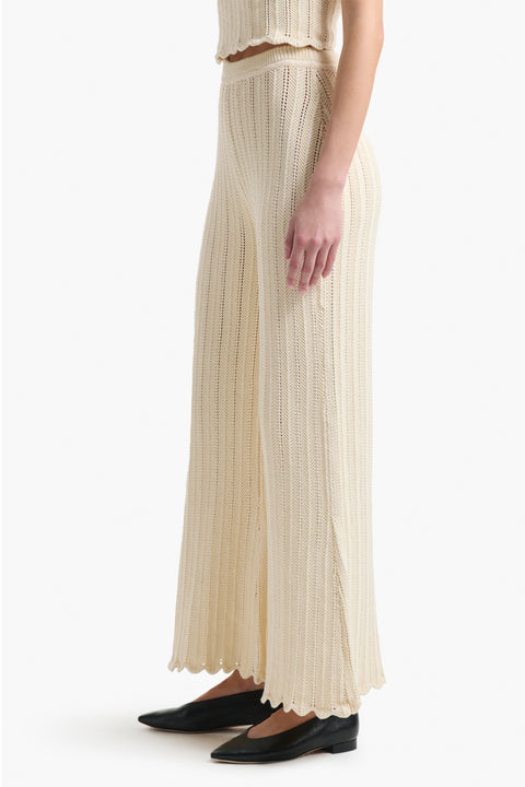 Up close of the side of the cream knitted pants on woman in black shoes.