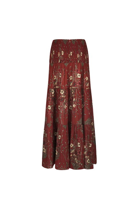 A long, tiered A-line skirt in a deep burgundy red fabric, decorated with an all-over vintage floral pattern in muted green, beige, and white, shown against a plain white background.