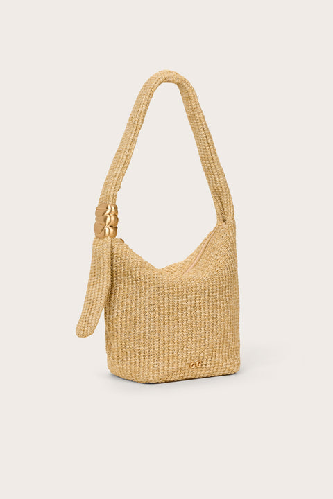 Side view of a tan, woven handbag that features a shoulder strap with gold hardware and zipper closure. 