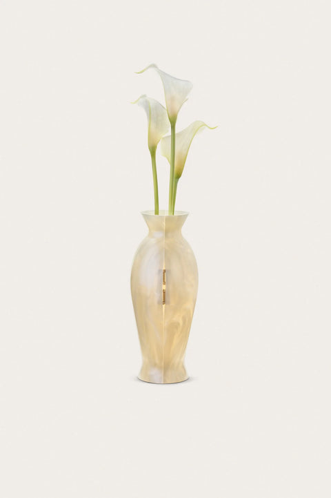 Pearlescent vase clutch standing on its own with white flowers on a white background