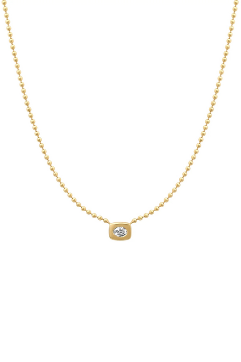 A small oval shaped diamond set in a  rectangular bezel setting, attached to a gold bead chain. 