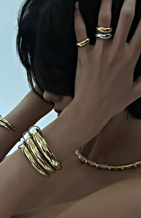 Model hand styled with gold jewelry featuring the piercing bangle.
