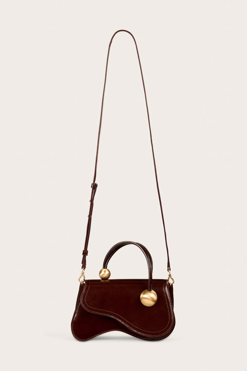 Sculptural brown handbag with long crossbody strap.