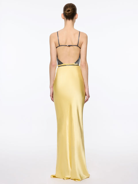 Woman wearing a yellow maxi dress with back cut out with a white background