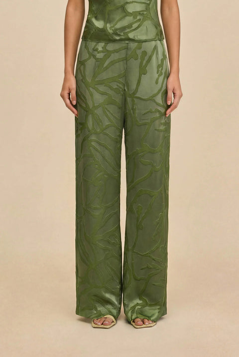 Detail shot of woman wearing a green matching top and wide leg pant against a white background