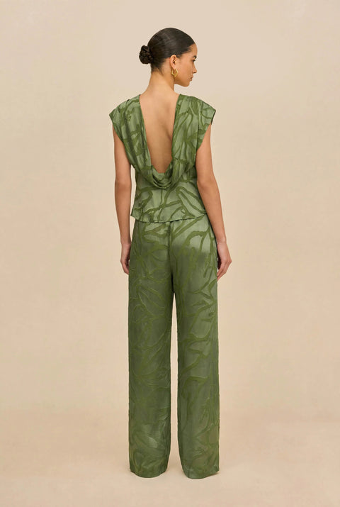 Back-facing shot of woman wearing a green matching top and wide leg pant against a white background