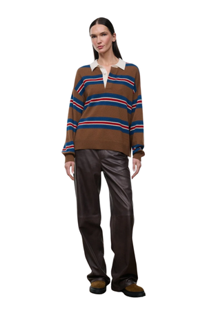 A model stands against a plain white background wearing a brown knit polo sweater with blue and red horizontal stripes, paired with dark brown leather pants and brown shoes.