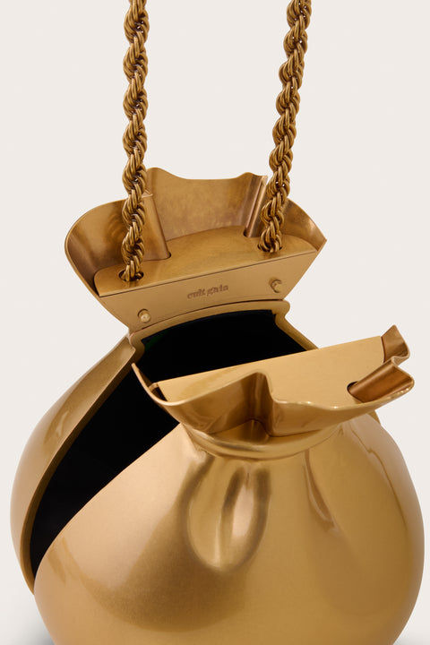Detail shot of a A gold-toned sculptural pouch clutch that features a twisted rope metal chain that opens from a hinge bottom. 