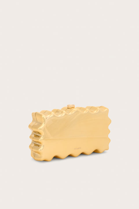 Side view of a metallic gold rectangular, acrylic clutch that features a wavy perimeter design and gold hardware. 