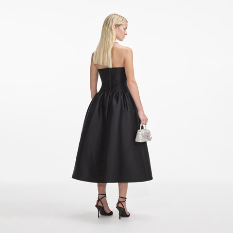 Woman facing away showing back of the black strapless midi dress.