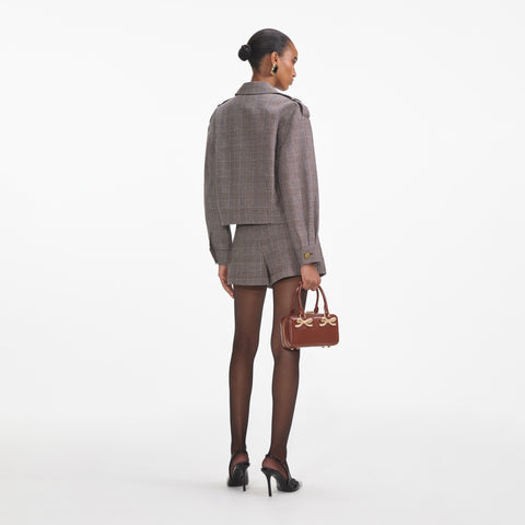 Woman facing away showing back of brown check mini skort with matching check jacket.