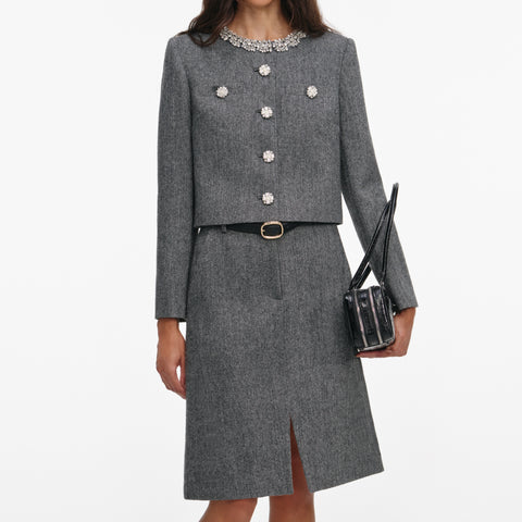 Gray herringbone jacket and skirt suit set with decorative buttons and a belt on a white background