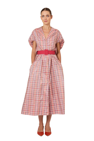 Woman wearing a pink plaid midi dress with a red belt on a white background