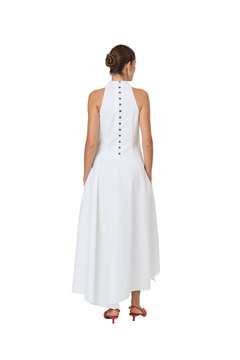 Woman facing away wearing a white sleeveless dress with black buttons on a white background