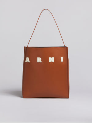 Front of brown leather tote bag with white letter patches.