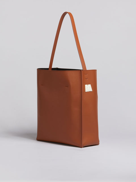 Back of brown leather tote with long strap.