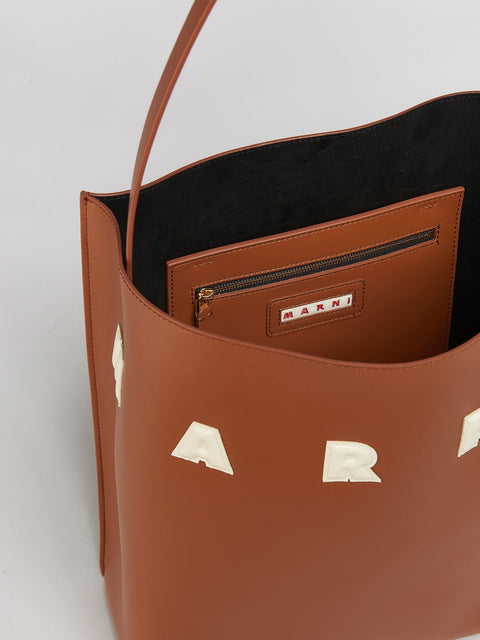 Up close of top and inside zipper pocket of the brown leather tote.