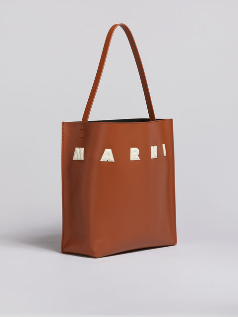 Another view of the brown leather tote with letter logo patches.