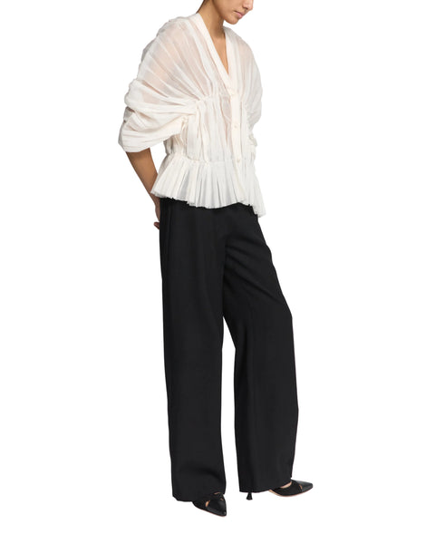 Person wearing a white blouse and black pants on a white background