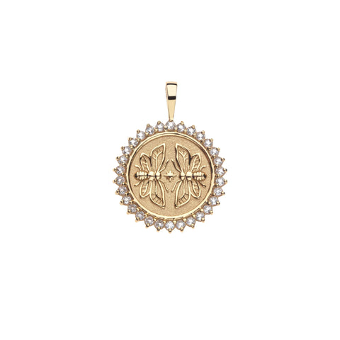 Gold coin pendant that features two twin bees surrounded by a ring of white topaz stones. 