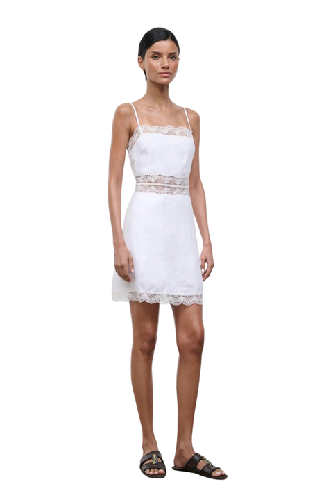 Woman wearing a white dress with lace details on a white background side angle