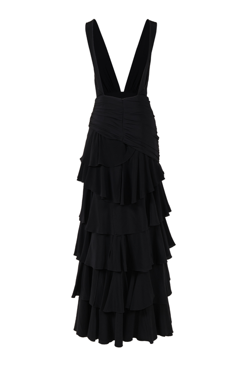 The low-cut back of a black maxi dress with a tiered skirt silhouette