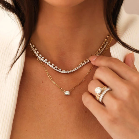 Woman wearing a yellow go tennis necklace and two other diamond necklaces. 