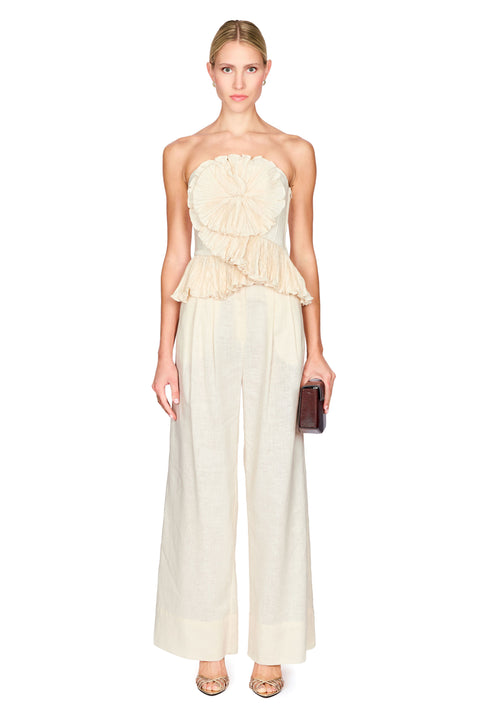 Woman wearing a strapless beige flower top with wide leg beige pants on a white background