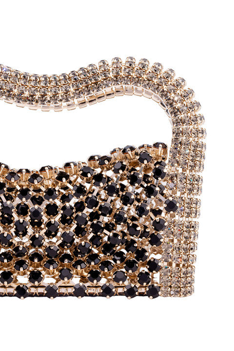 A close-up of a rhinestone-embellished handbag on a plain white background. The bag features a wavy top handle and a structured body covered in rows of black round crystals over a gold-tone base, with clear crystals forming the handle and side borders.