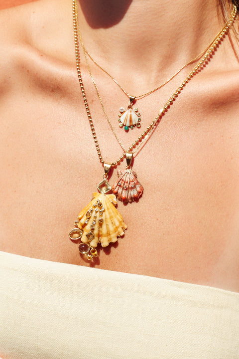 Stack of shell pendants on various chains worn by a model.