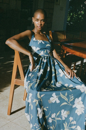 Model sitting in a chair wearing the navy hisbiscus print dress.