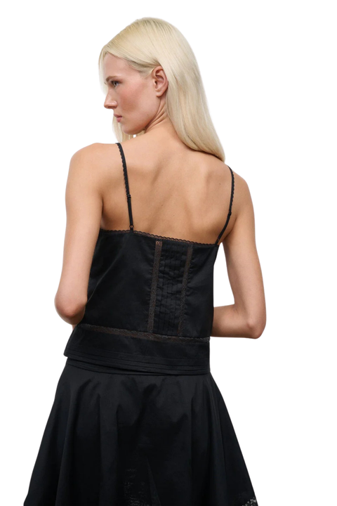 Back angle of A woman wearing a black sleeveless top with a matching skirt