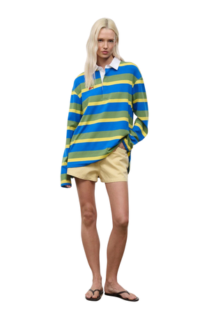 Woman wearing a blue, green, and yellow striped shirt with a white collar on a white background