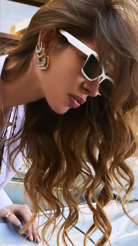 Side shot of model wearing stack of gold huggie earrings.