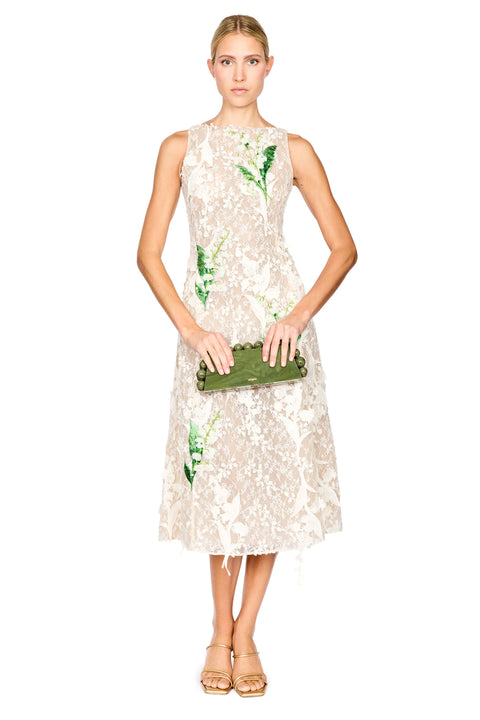 A model wearing a sleeveless cream lace midi dress with green floral applique, paired with gold high-heeled sandals, against a plain white background.