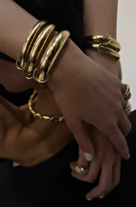 Model arms wearing stack of piercing bangle bracelets.