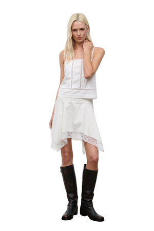 A woman wearing a white lace midi skirt with a matching white sleeveless top