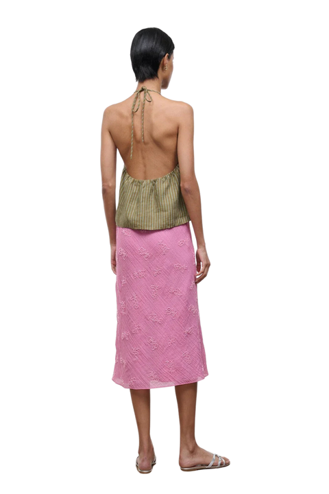 The back angle of a woman wearing a pink midi skirt with beaded embellishments and a drawstring waist
