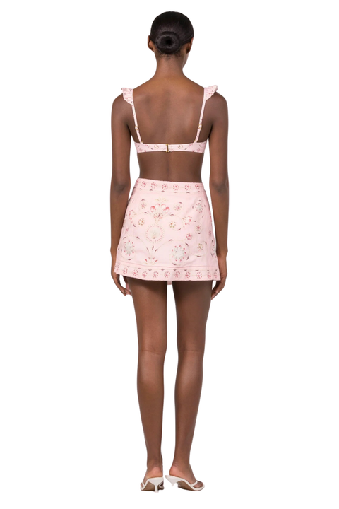 A woman wearing a pink multicolor swim cover up mini skirt