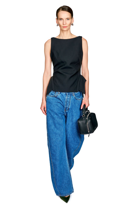 A model wearing a black sleeveless top with a peplum hem, wide-leg blue jeans, and a small black handbag, photographed against a solid white background.