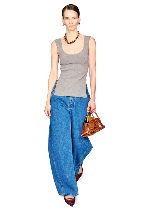A model wearing a gray ribbed knit tank top, wide-leg blue denim jeans, a brown beaded necklace, and holding a brown leather handbag against a plain white background.