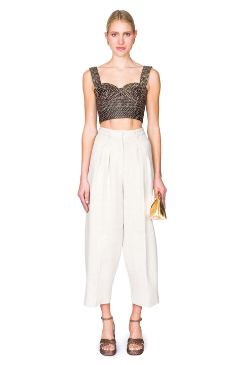 Woman wearing a black and tan woven  bustier crop top and white pants on a white background