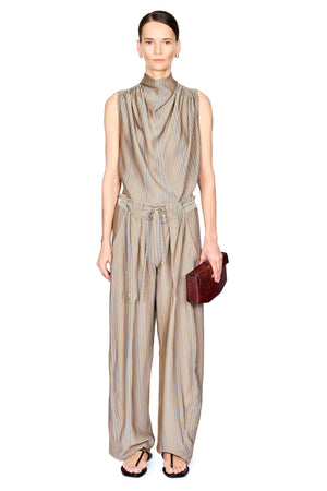 A model stands against a white background wearing a sleeveless, high-neck top and matching pants in a beige and brown vertical stripe pattern. The pant features a gathered waist with a matching fabric tie belt and wide-leg trousers.