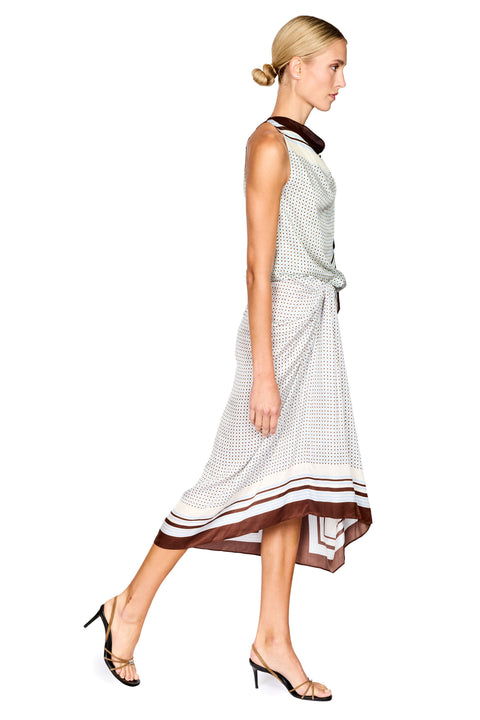 A woman modeling a sleeveless two piece set with a white and brown checkered pattern, featuring a dark brown collar and hem, paired with black strappy heels against a plain white background.