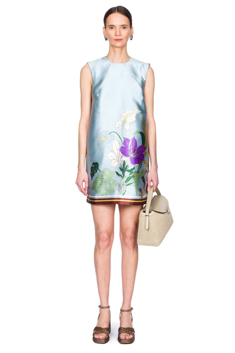 Woman wearing a light blue mini dress with floral patterns on a white background