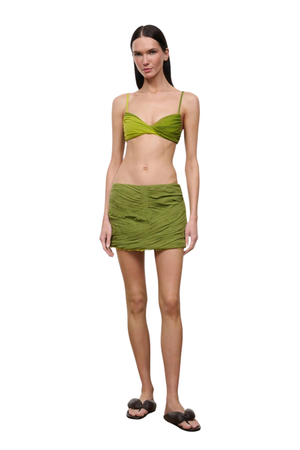 Woman wearing a green mini skirt cover up set on a white background