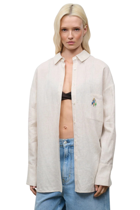 Close-up of a woman wearing a beige oversized linen button down with pocket embroidery